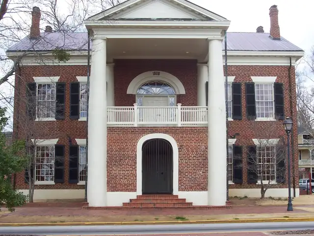 Two-storey red-brick 1836 courthouse with white columns, an upper balcony and black shutters, now the Dahlonega Gold Museum
